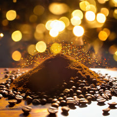 A large pile of ground and full coffee beans on a wood table with golden lights in the background